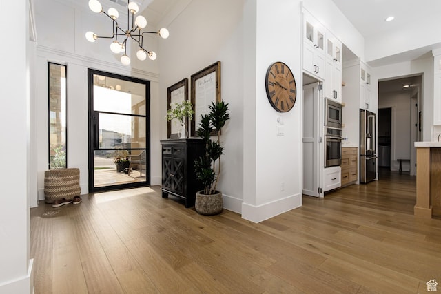 entryway featuring a chandelier, recessed lighting, wood-type flooring, and baseboards