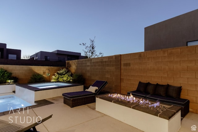 view of patio / terrace with an in ground hot tub, a fenced backyard, and an outdoor living space with a fire pit