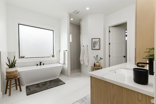 full bath with visible vents, a freestanding bath, recessed lighting, a walk in shower, and vanity