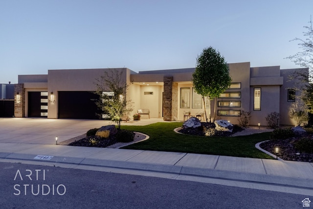 view of front of home featuring an attached garage, a front lawn, driveway, and stucco siding