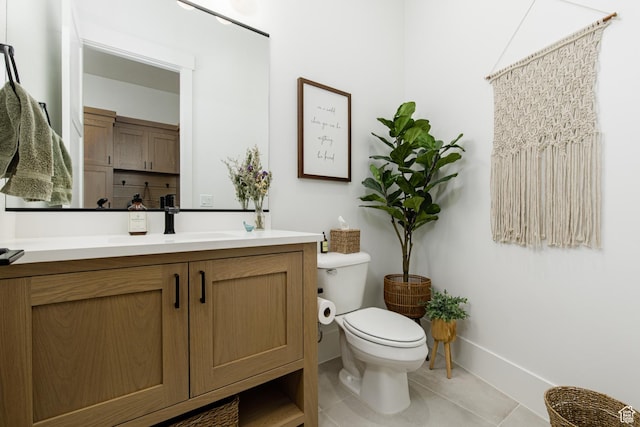 bathroom with tile patterned flooring, vanity, baseboards, and toilet