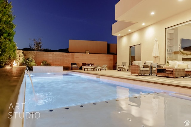 pool at night with an outdoor living space, a patio, and a fenced backyard