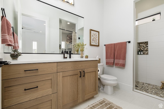 bathroom with tiled shower, vanity, toilet, and tile patterned flooring