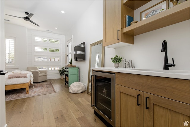 kitchen featuring open shelves, a sink, light countertops, light wood-style floors, and beverage cooler