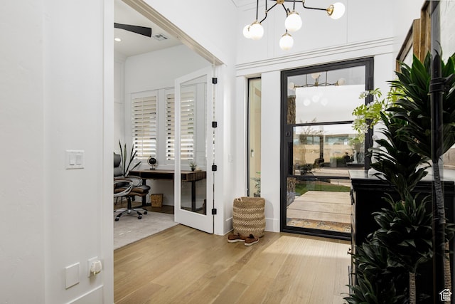 foyer entrance with a healthy amount of sunlight, a notable chandelier, visible vents, and wood finished floors
