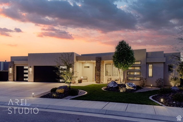 view of front of house featuring driveway, a lawn, a garage, and stucco siding
