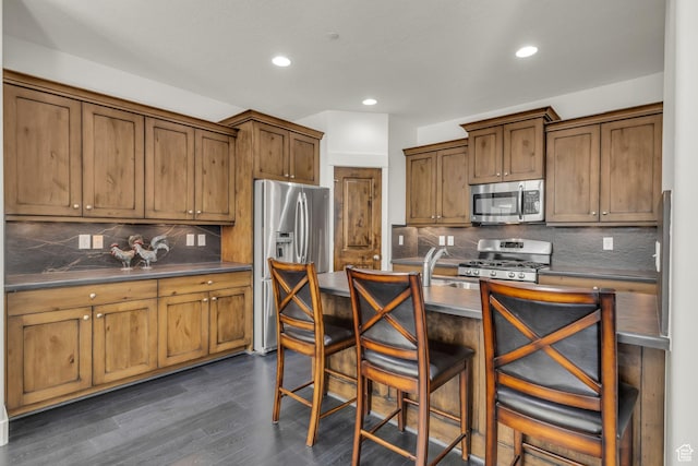 865 W Benjamin Pl, Kamas, UT 84036 - kitchen featuring appliances with stainless steel finishes, dark countertops, dark wood-style floors, and a kitchen breakfast bar