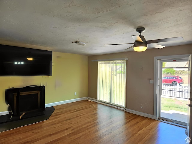 1989 W 1800 N, St George, UT 84770 - unfurnished living room with ceiling fan, a wood stove, visible vents, wood finished floors, and baseboards