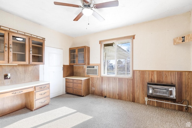 unfurnished office with built in desk, heating unit, a wainscoted wall, wood walls, and light colored carpet