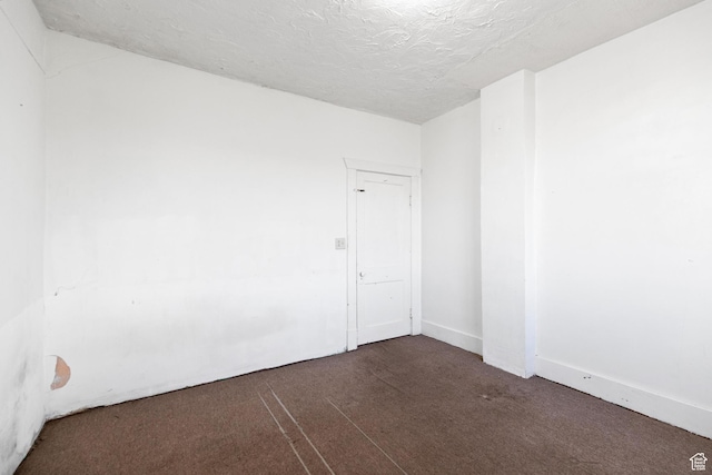 unfurnished room featuring dark carpet and a textured ceiling