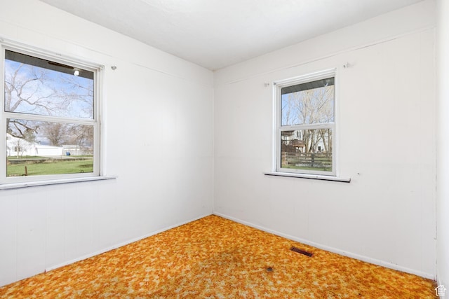 carpeted spare room featuring visible vents, baseboards, and plenty of natural light