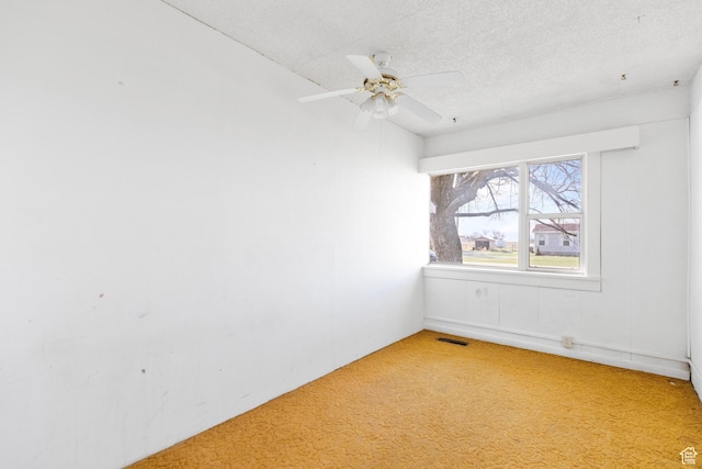 spare room with a textured ceiling, light colored carpet, ceiling fan, and visible vents
