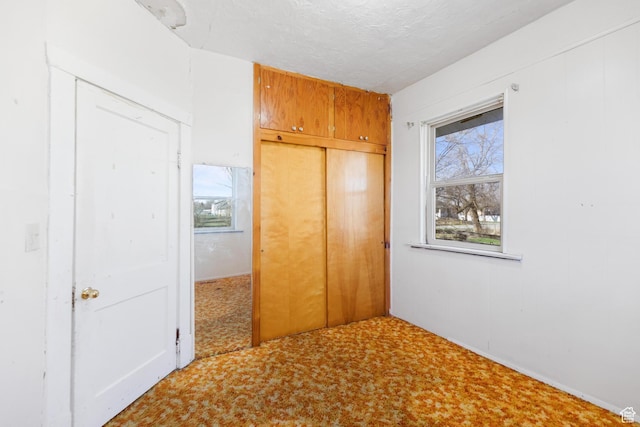 unfurnished bedroom with a closet, carpet flooring, and a textured ceiling