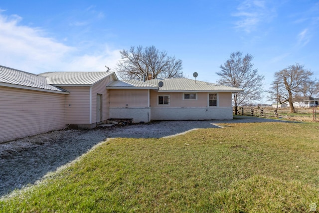 back of property with metal roof and a lawn