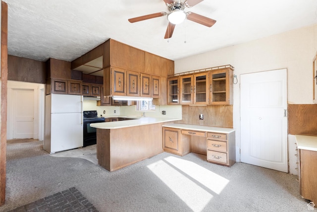 kitchen with freestanding refrigerator, glass insert cabinets, a peninsula, black electric range, and light countertops
