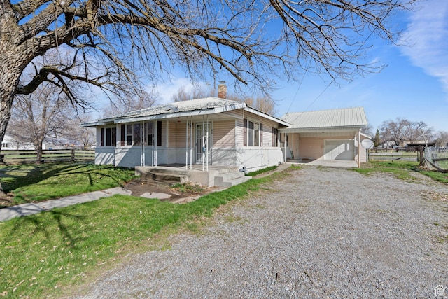 view of front of home featuring driveway, fence, a chimney, and covered porch