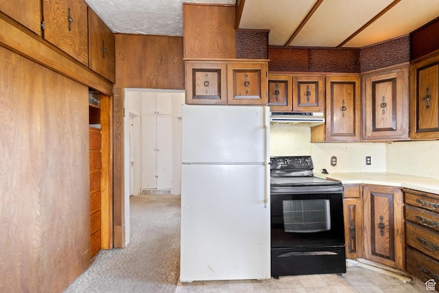 kitchen with black / electric stove, light countertops, freestanding refrigerator, under cabinet range hood, and brown cabinets