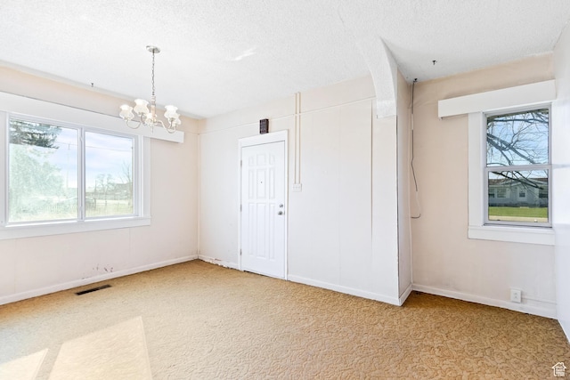 spare room featuring visible vents, a textured ceiling, an inviting chandelier, and a healthy amount of sunlight