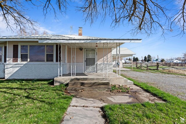 bungalow featuring a chimney, a front lawn, metal roof, fence, and covered porch