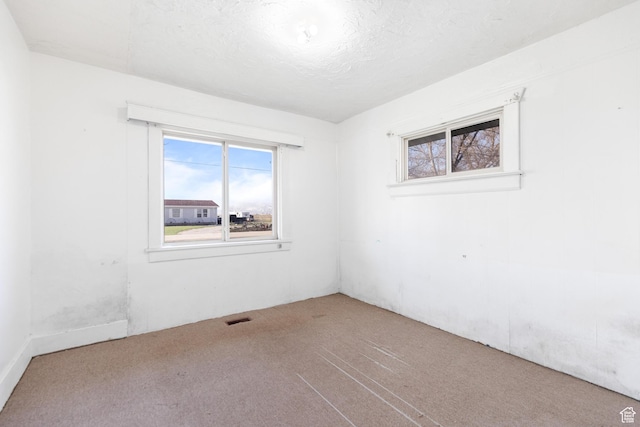 carpeted spare room with a textured ceiling and visible vents