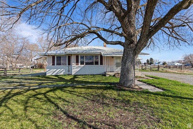 view of front of house featuring a front yard, metal roof, fence, and a chimney