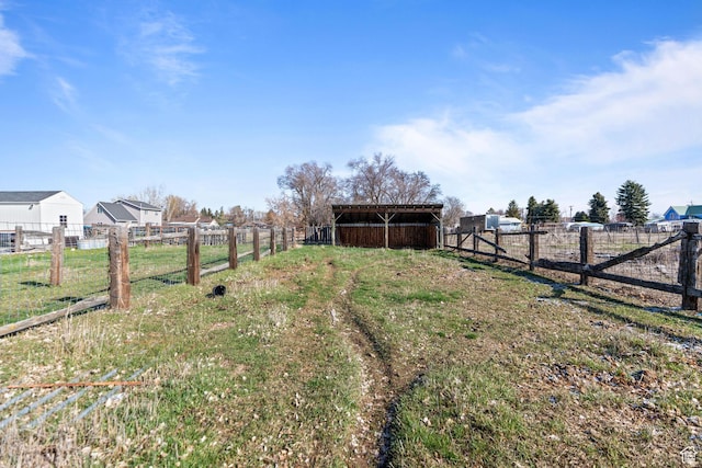 view of yard with a rural view, an outdoor structure, fence, and an outbuilding