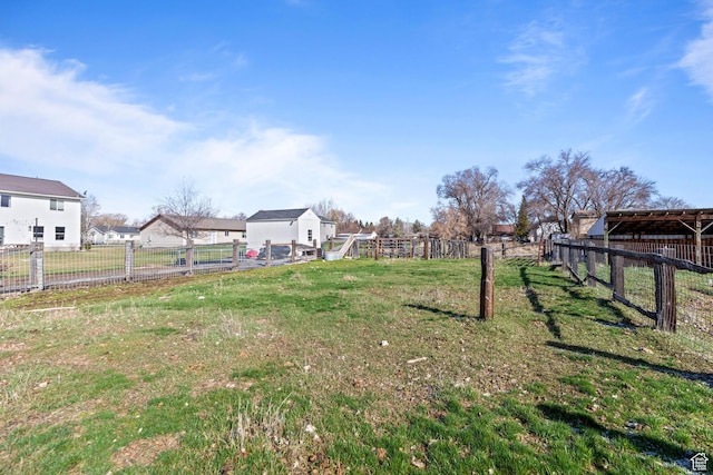 view of yard featuring a residential view, fence, and an outbuilding