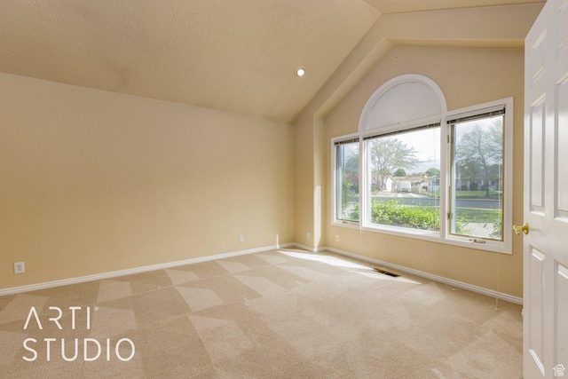 empty room with visible vents, baseboards, vaulted ceiling, and light carpet