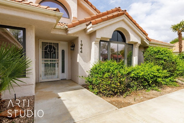 doorway to property with a tile roof and stucco siding