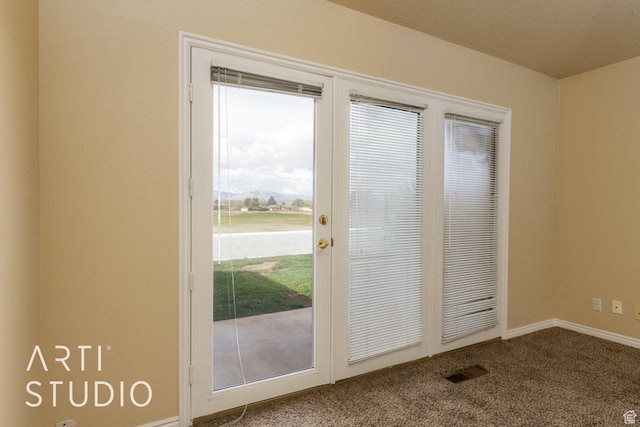 doorway to outside featuring visible vents, baseboards, and dark colored carpet