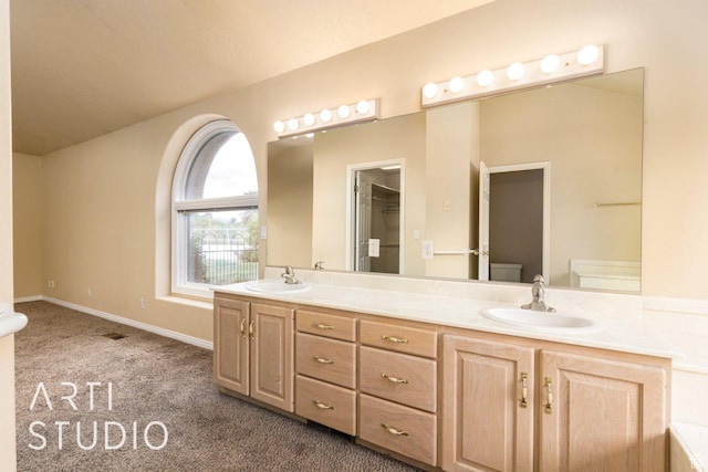 bathroom featuring double vanity, baseboards, a sink, and toilet