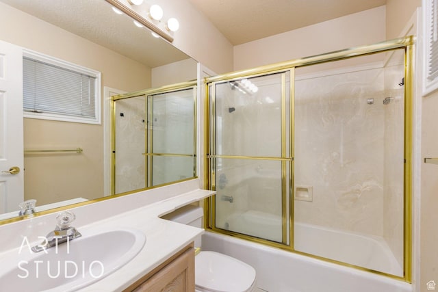 bathroom featuring enclosed tub / shower combo, vanity, a textured ceiling, and toilet