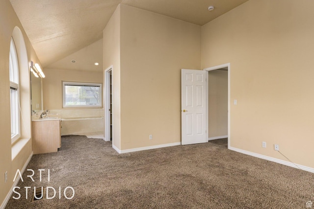 unfurnished bedroom with high vaulted ceiling, dark colored carpet, and baseboards