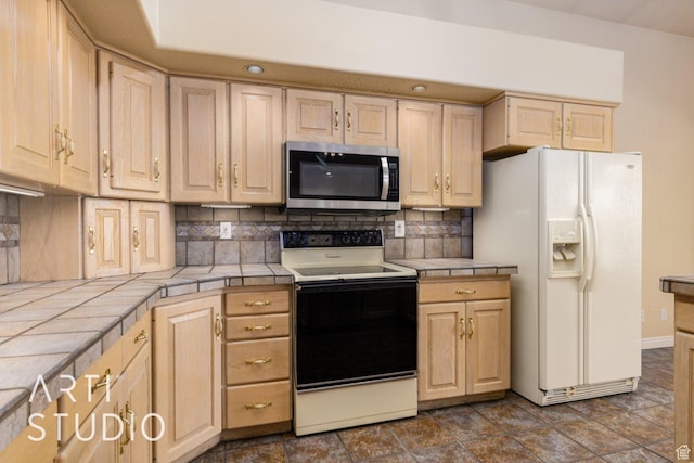 kitchen with white fridge with ice dispenser, light brown cabinets, electric stove, tile counters, and stainless steel microwave