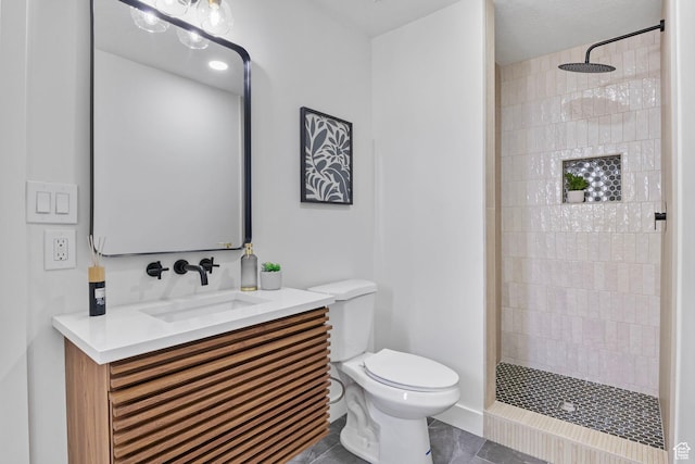 full bath featuring toilet, tile patterned floors, vanity, and a tile shower