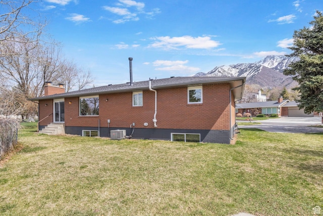 rear view of property featuring brick siding, a mountain view, entry steps, and a yard