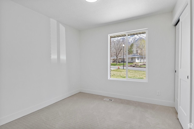 unfurnished bedroom featuring light carpet, visible vents, multiple windows, and a closet