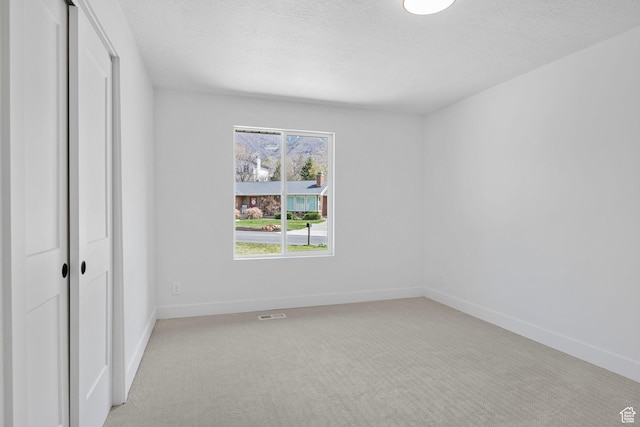 unfurnished bedroom with a closet, baseboards, light carpet, and a textured ceiling