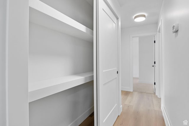 hallway featuring light wood-style floors and baseboards