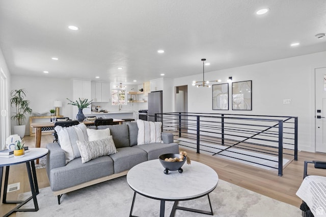 living area with recessed lighting, light wood-style flooring, and an inviting chandelier