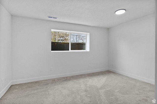 carpeted empty room with visible vents, baseboards, and a textured ceiling