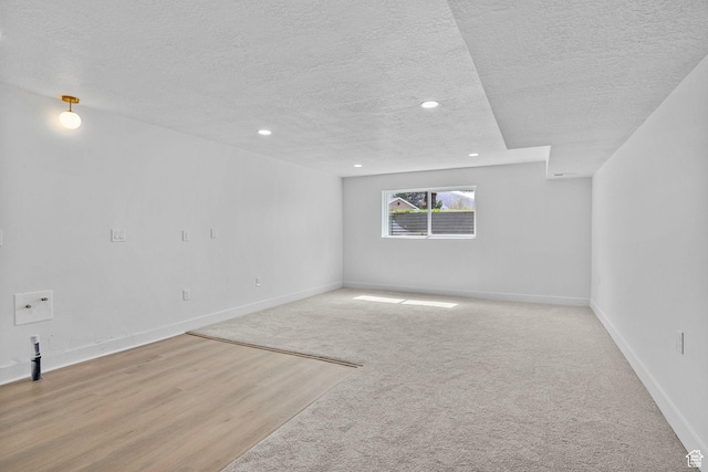 empty room featuring recessed lighting, light colored carpet, a textured ceiling, and baseboards