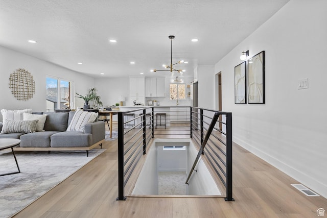 staircase featuring wood finished floors, baseboards, visible vents, and recessed lighting