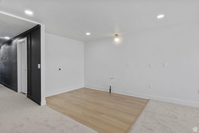 basement with baseboards, recessed lighting, light colored carpet, and a textured ceiling