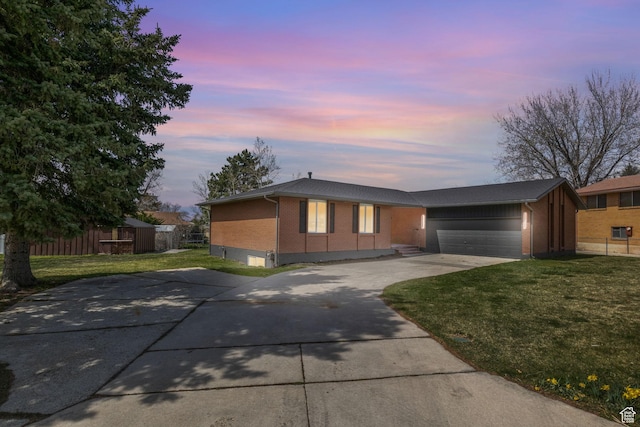 view of front facade with a garage, fence, concrete driveway, brick siding, and a front lawn