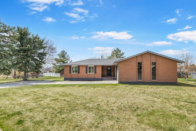 view of front of house with driveway, a front yard, fence, and brick siding