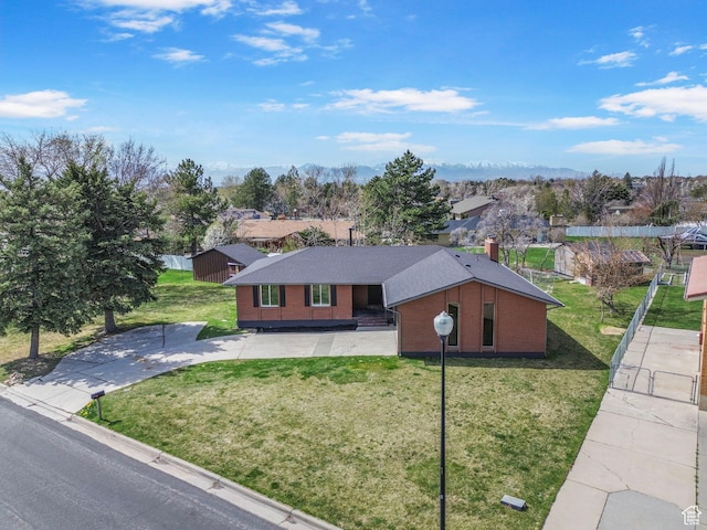 ranch-style house featuring a mountain view, brick siding, a chimney, and a front lawn