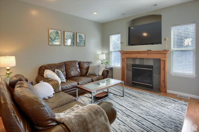 living room featuring visible vents, baseboards, recessed lighting, wood finished floors, and a tile fireplace