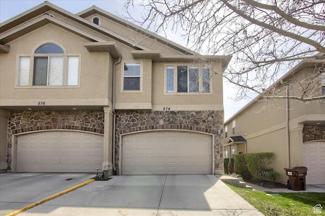 view of front facade with stone siding, driveway, and stucco siding