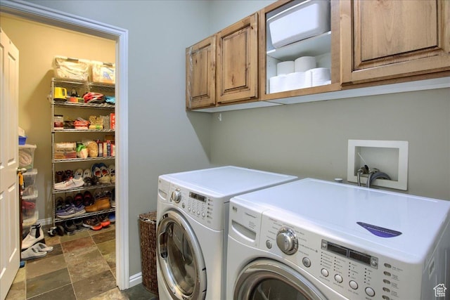 clothes washing area with stone finish floor, separate washer and dryer, and cabinet space
